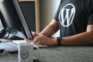 Man working on computer while wearing shiirt with WordPress logo